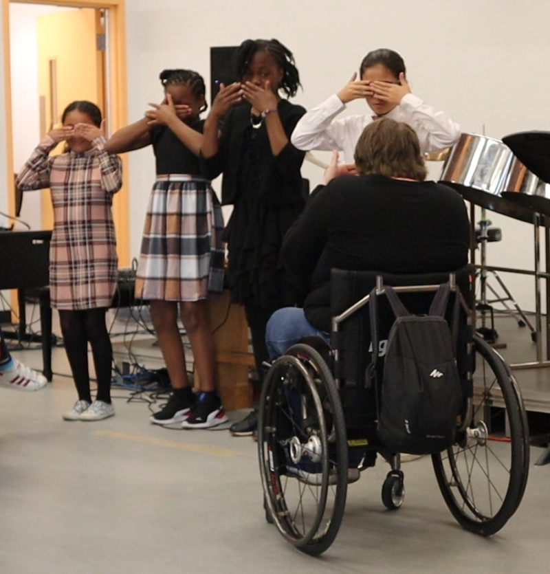 A group of students performing the song in ASL. Diane is helping them in the front.