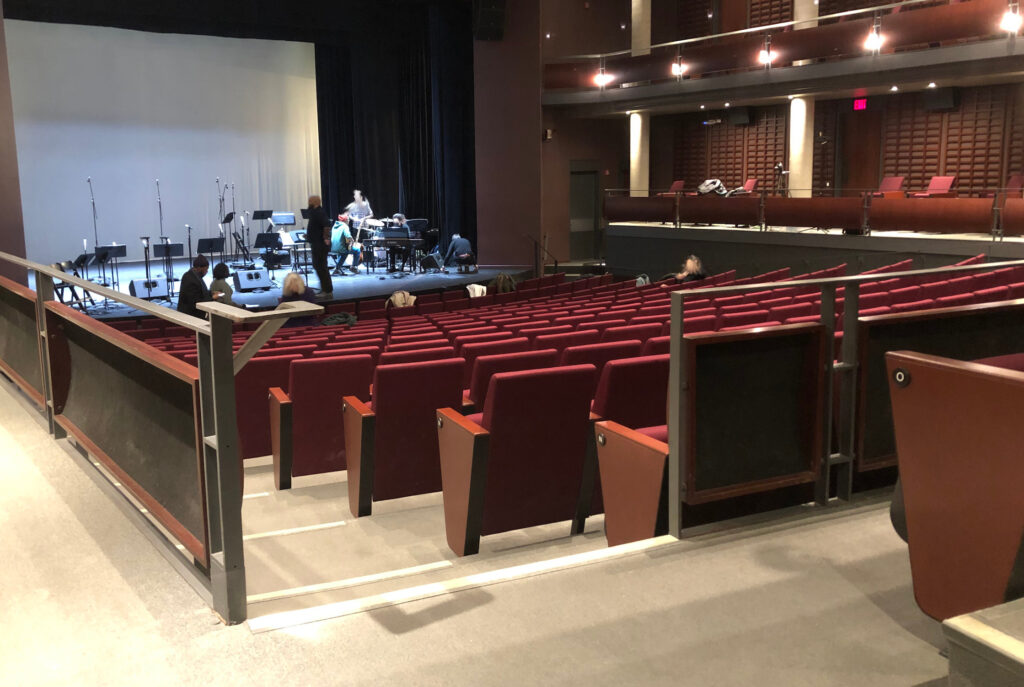 Inside the theatre, with a few on the stage from the accessible seating in the audience.