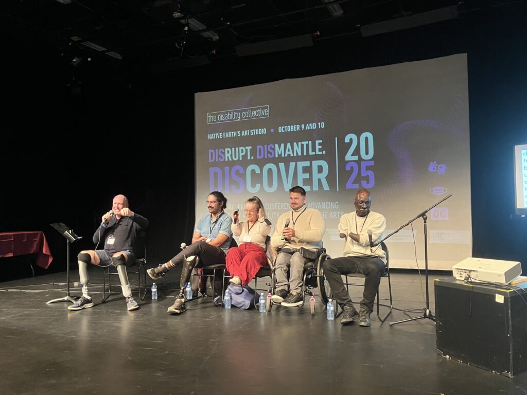 A panel of five participants, five actors with disabilities, sitting on chairs in front of the audience.