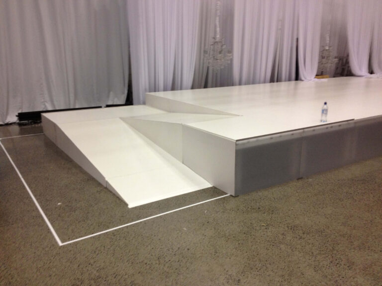 Une rampe d'accès blanche menant à une scène blanche.