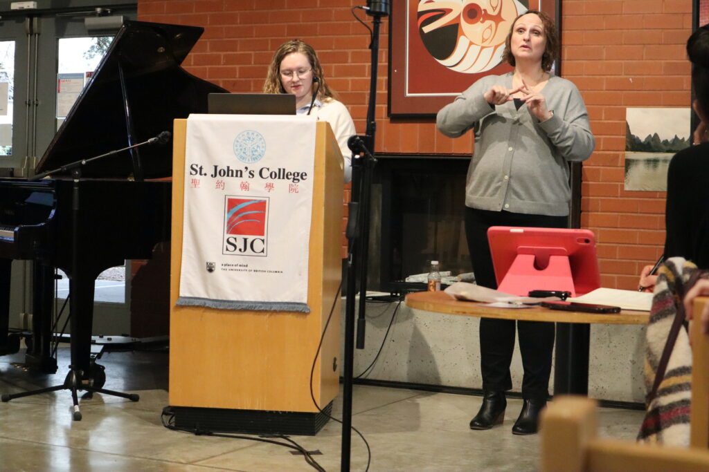 A white woman with glasses presenting from a wooden stand.