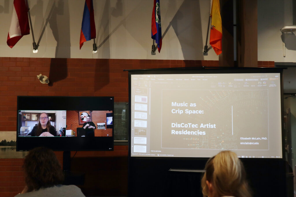 A white woman with glasses wearing a black top presents remotely. Her presentation called Music as a Crip Space is displayed on the larger screen on the right.