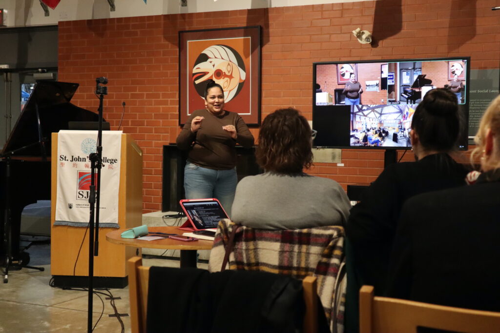 An indigenous woman shows ASL signs as a music performer for her workshop about sign music.
